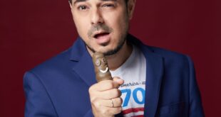 סטנדאפיסט על במה מופיע מול מסך המציג נתוני בינה מלאכותית