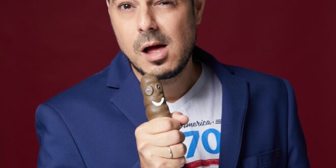 סטנדאפיסט על במה מופיע מול מסך המציג נתוני בינה מלאכותית